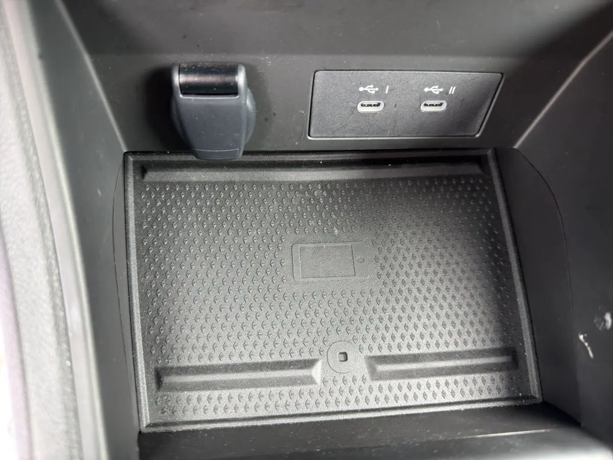 Gros plan sur la zone de recharge sans fil et ports USB-C avant dans l’habitacle noir du Renault Symbioz 2025.
