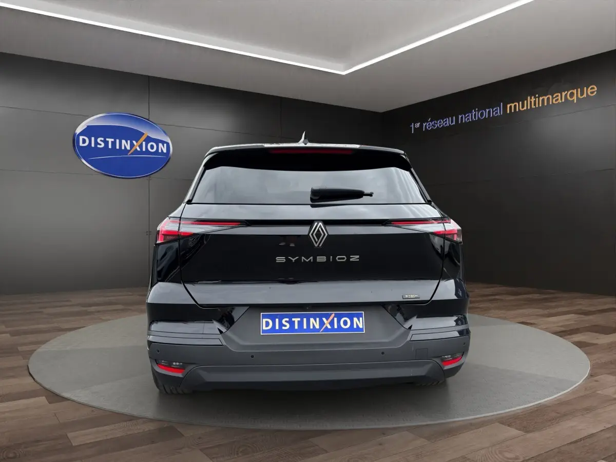 Vue arrière d'une Renault SYMBIOZ noire 2025 avec feux LED fins et logo centré sur un fond intérieur showroom.