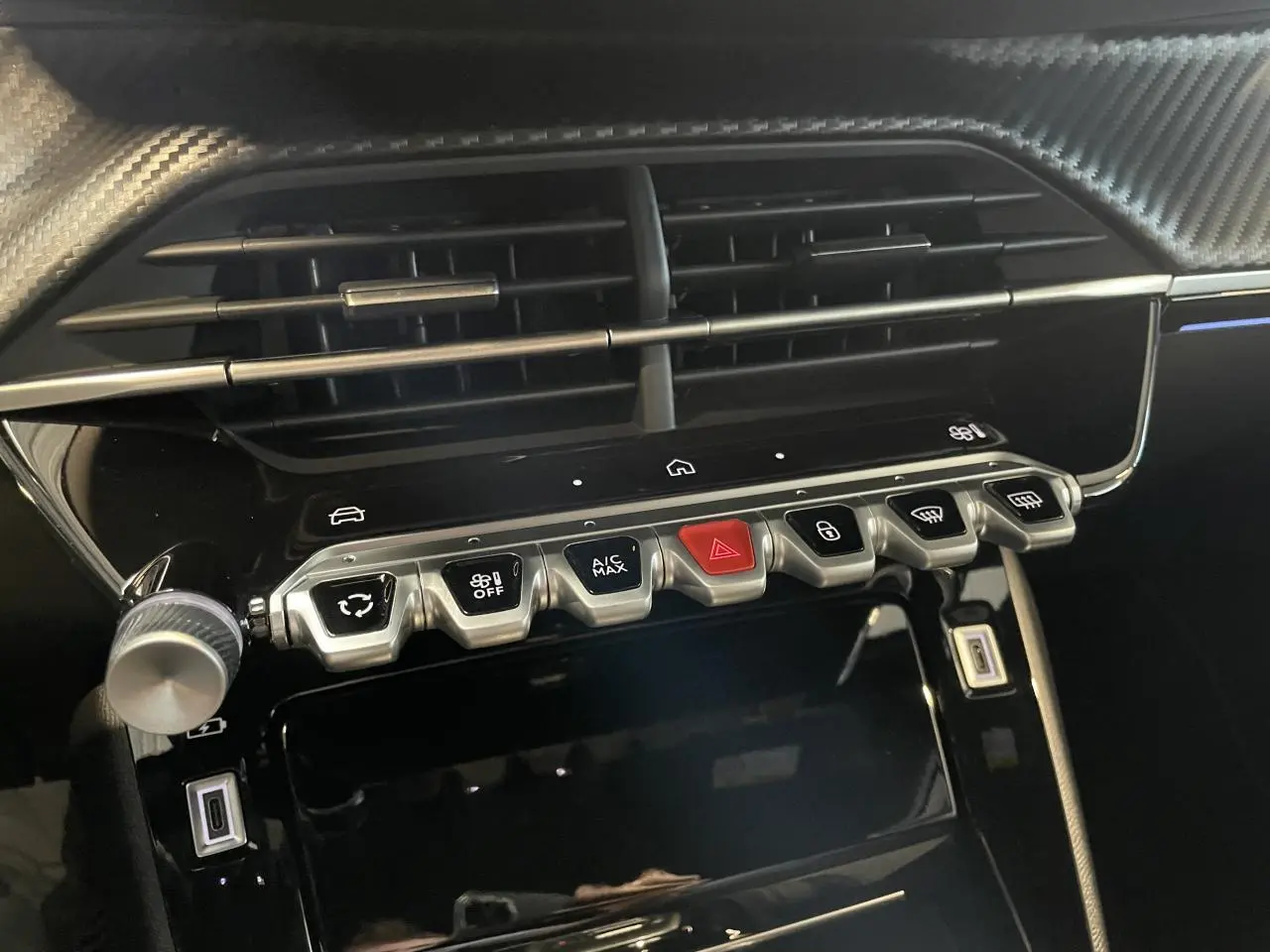 Vue rapprochée de la console centrale intérieure noire avec commandes et prises USB du Peugeot 2008 blanc hybride 2026.