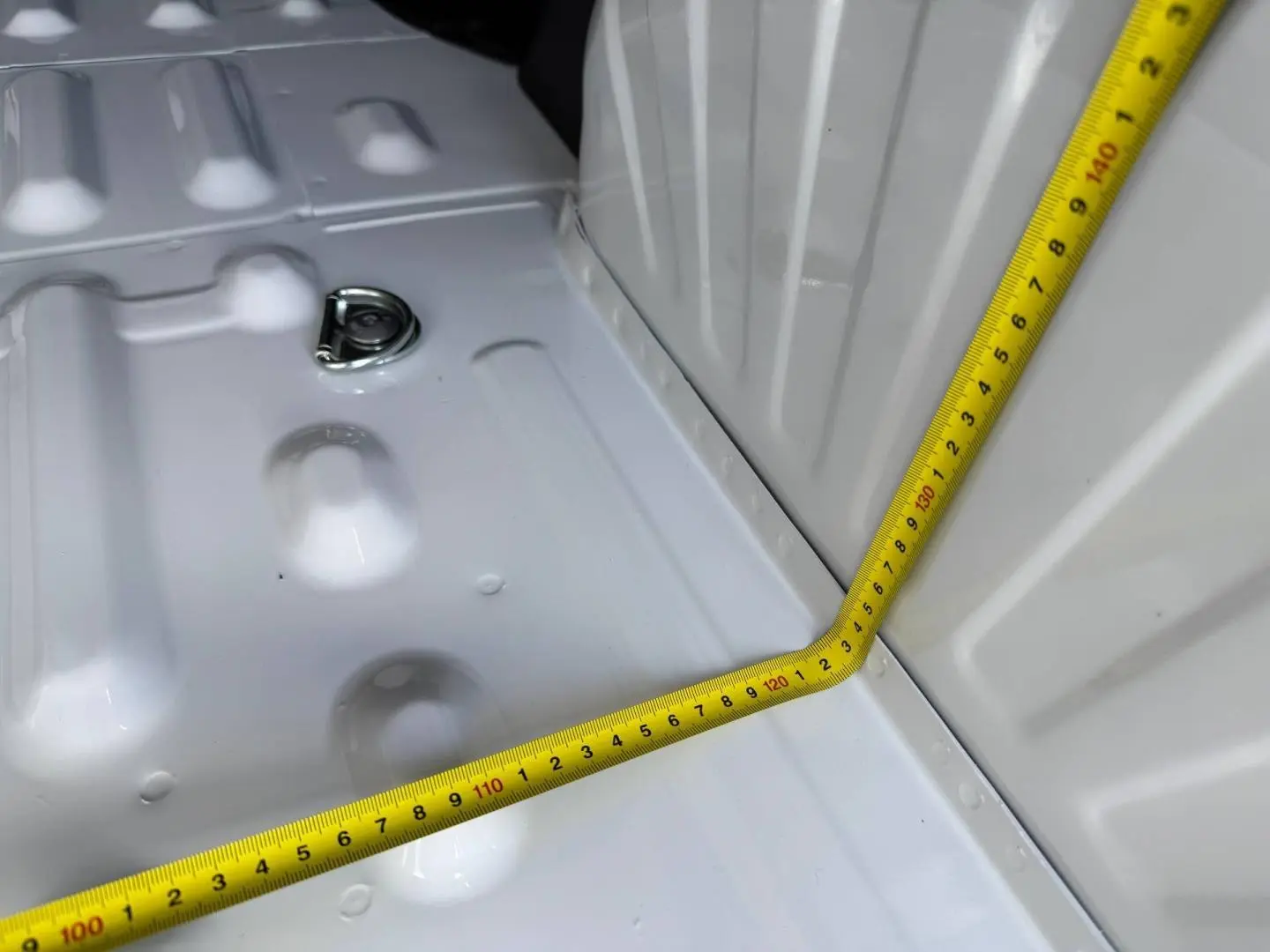 Détail de la zone de chargement blanche du Peugeot Partner 2026 avec mètre ruban jaune mesurant l'espace intérieur.