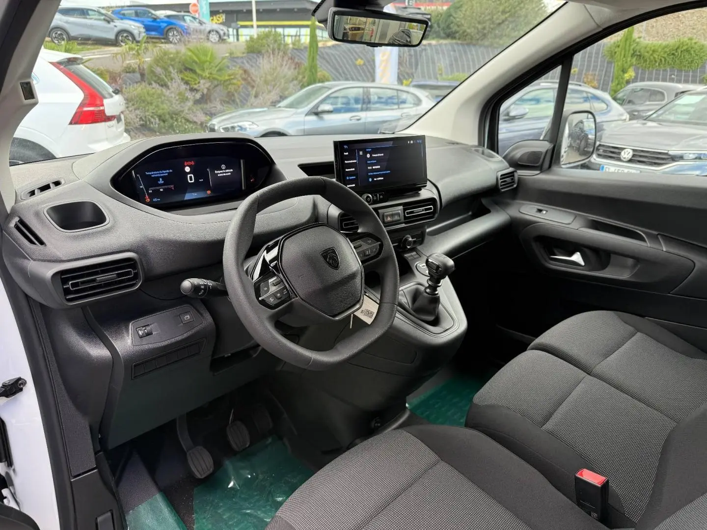 Vue intérieure côté conducteur du Peugeot Partner blanc Icy 2026, avec tableau de bord numérique et volant multifonction.