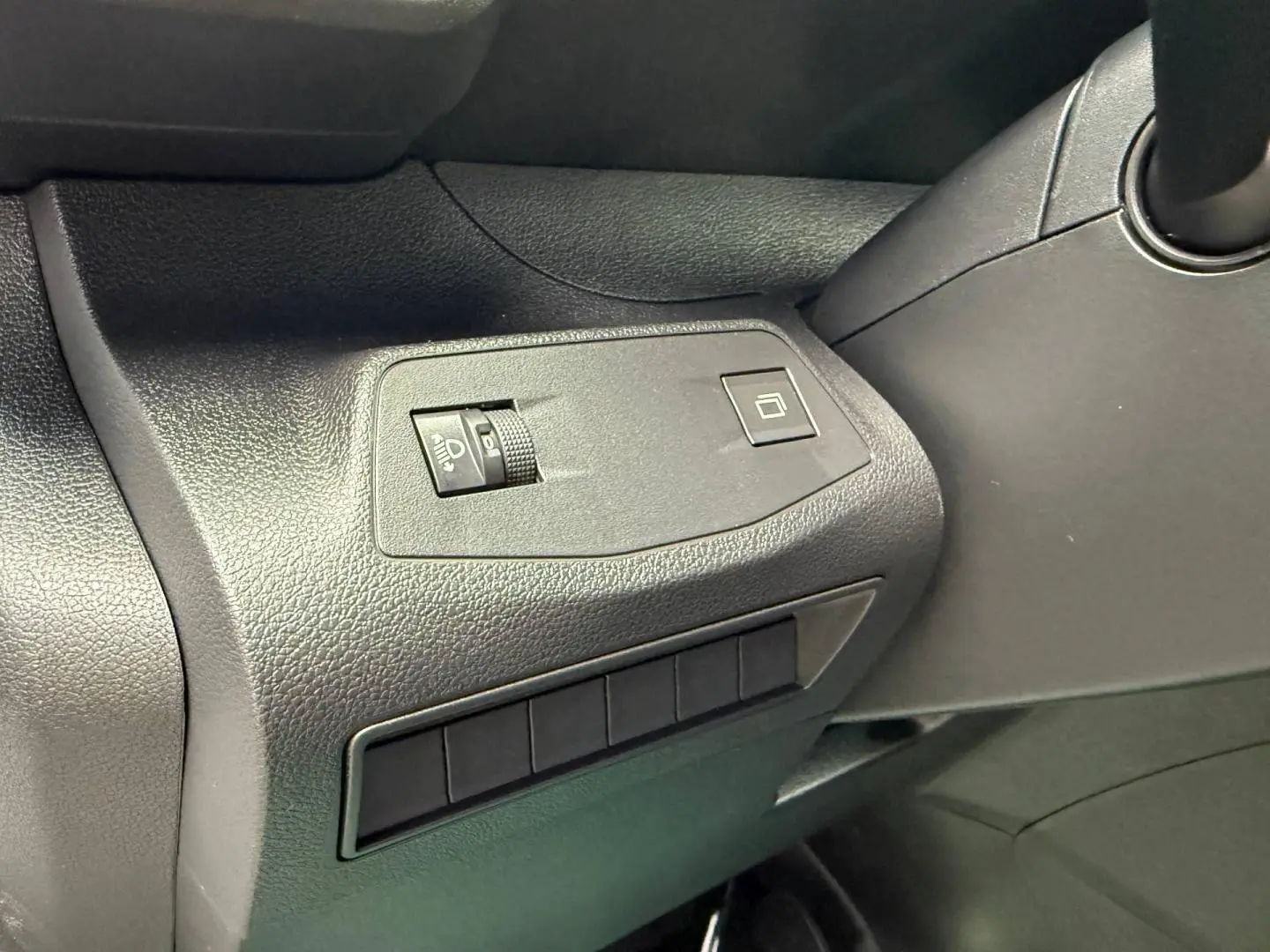 Gros plan sur les commandes de réglage des phares et de la fermeture de la porte côté conducteur du Peugeot Partner blanc Icy 2026.