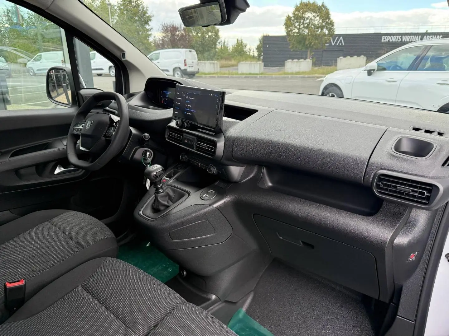 Vue intérieure côté conducteur du Peugeot Partner 2026 blanc Icy, montrant tableau de bord moderne et boîte manuelle.