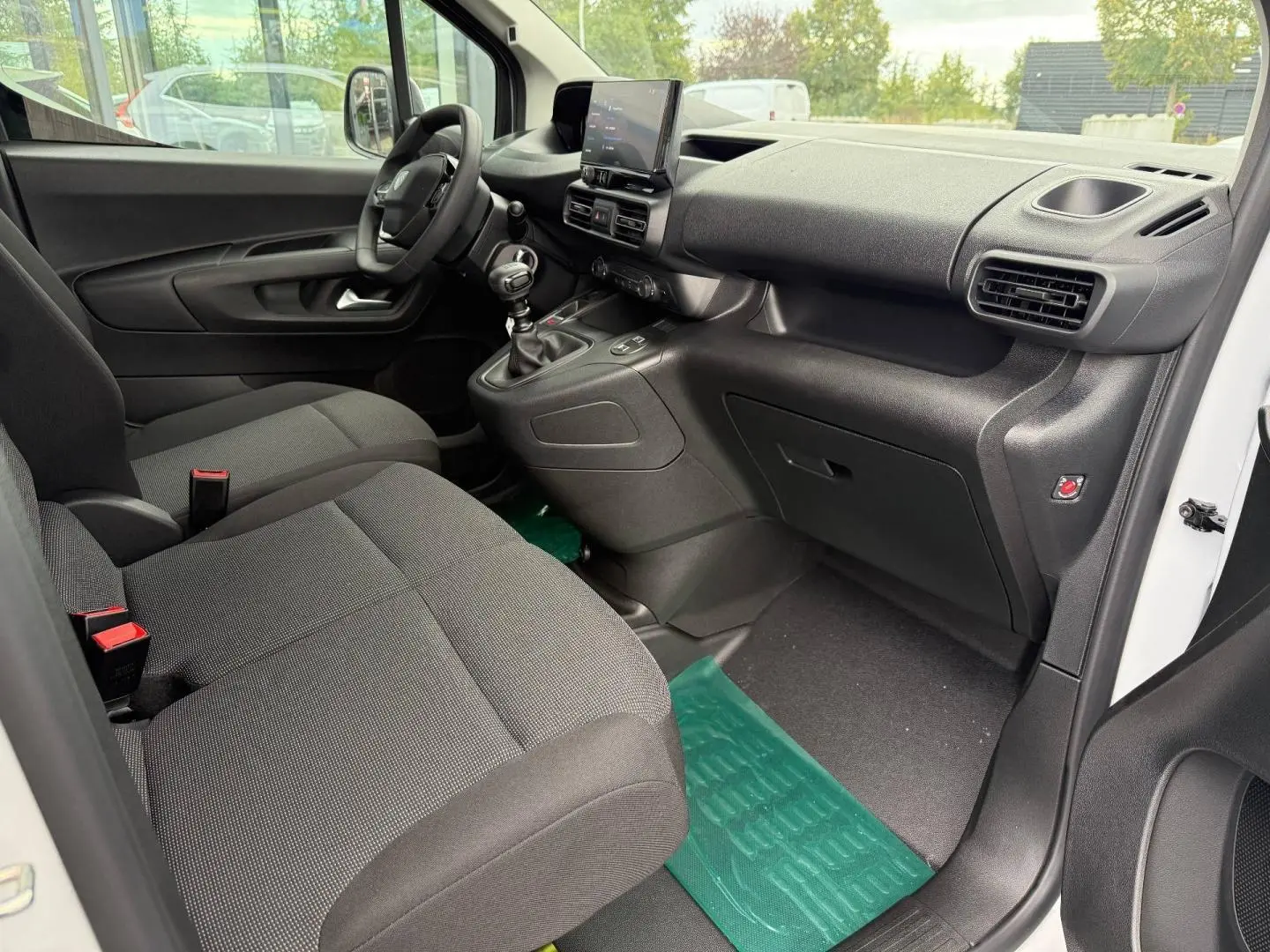Intérieur avant droit du Peugeot Partner blanc Icy 2026, avec sièges tissu Curitiba et tableau de bord noir moderne.