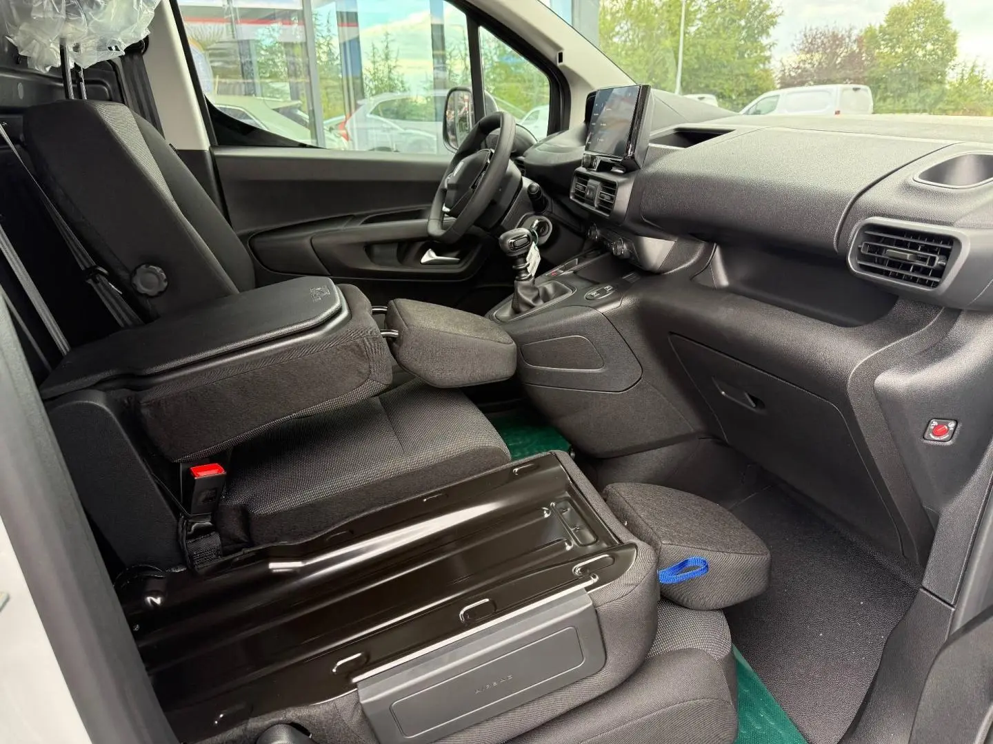 Vue intérieure côté conducteur du Peugeot Partner blanc Icy 2026, montrant les sièges et le tableau de bord noir.