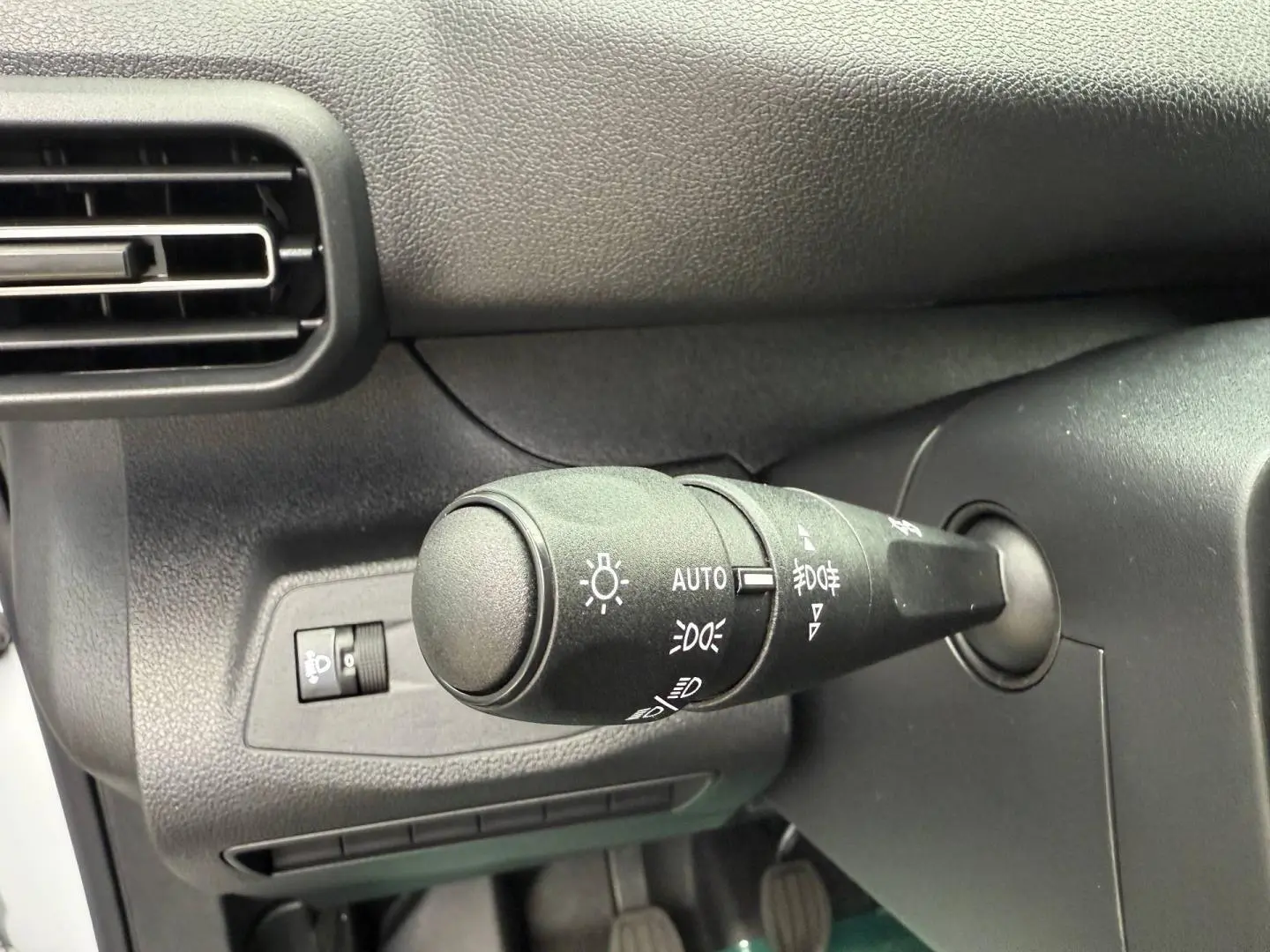 Gros plan sur la commande des phares du tableau de bord du Peugeot Partner blanc Icy, intérieur noir.