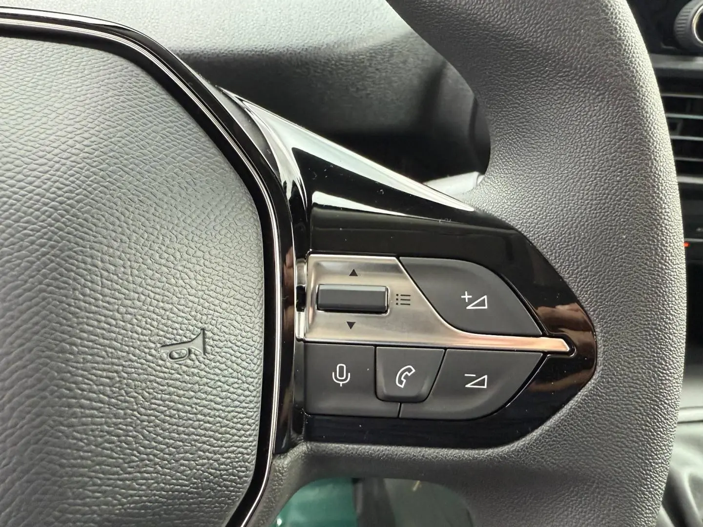 Gros plan sur les commandes multifonctions noires du volant du Peugeot Partner blanc Icy, côté droit.