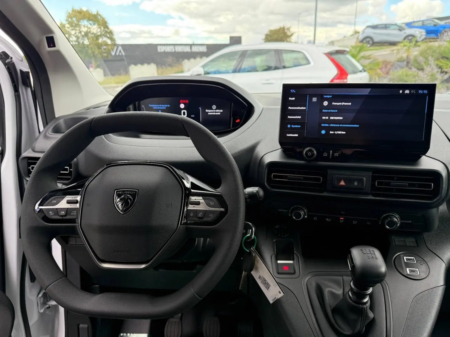 Vue intérieure du poste de conduite du Peugeot Partner blanc Icy 2026, volant multifonction et écran tactile central.