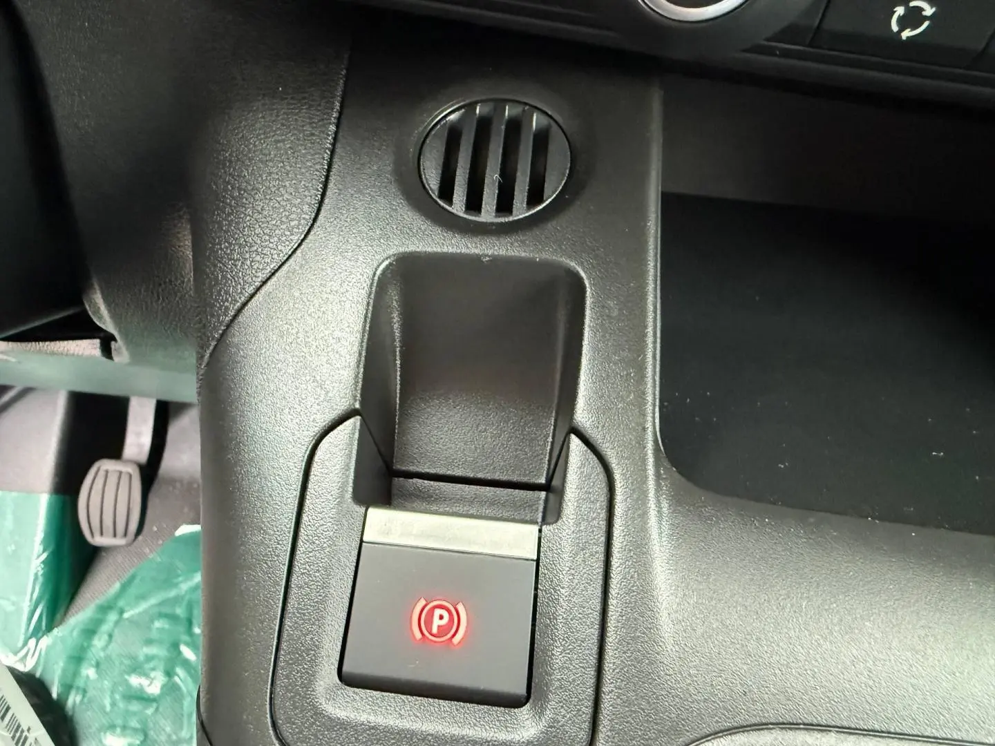 Gros plan sur la commande de frein à main électrique rouge dans l'habitacle du Peugeot Partner blanc Icy.