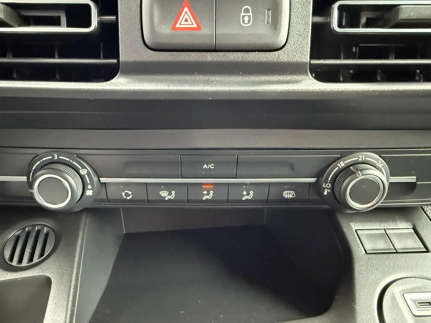 Vue rapprochée de la console centrale noire du Peugeot Partner 2026, montrant les commandes de climatisation manuelle.