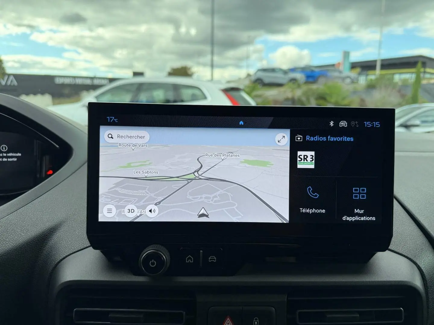 Écran tactile central affichant la navigation GPS et les radios favorites dans un Peugeot Partner blanc Icy, vue intérieure frontale.
