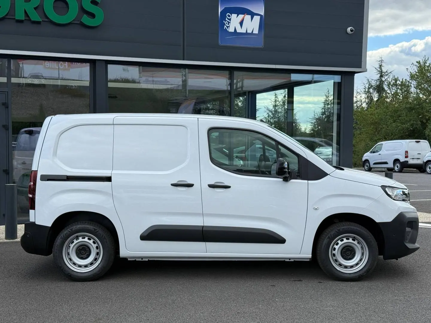 Peugeot Partner blanc Icy vu de profil côté droit, avec porte latérale coulissante et protections noires.