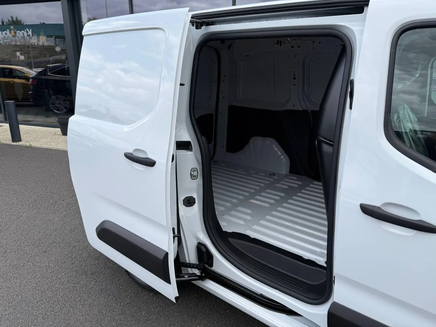 Vue côté droit en gros plan du Peugeot Partner blanc Icy avec porte latérale coulissante ouverte dévoilant l’espace de chargement vide.