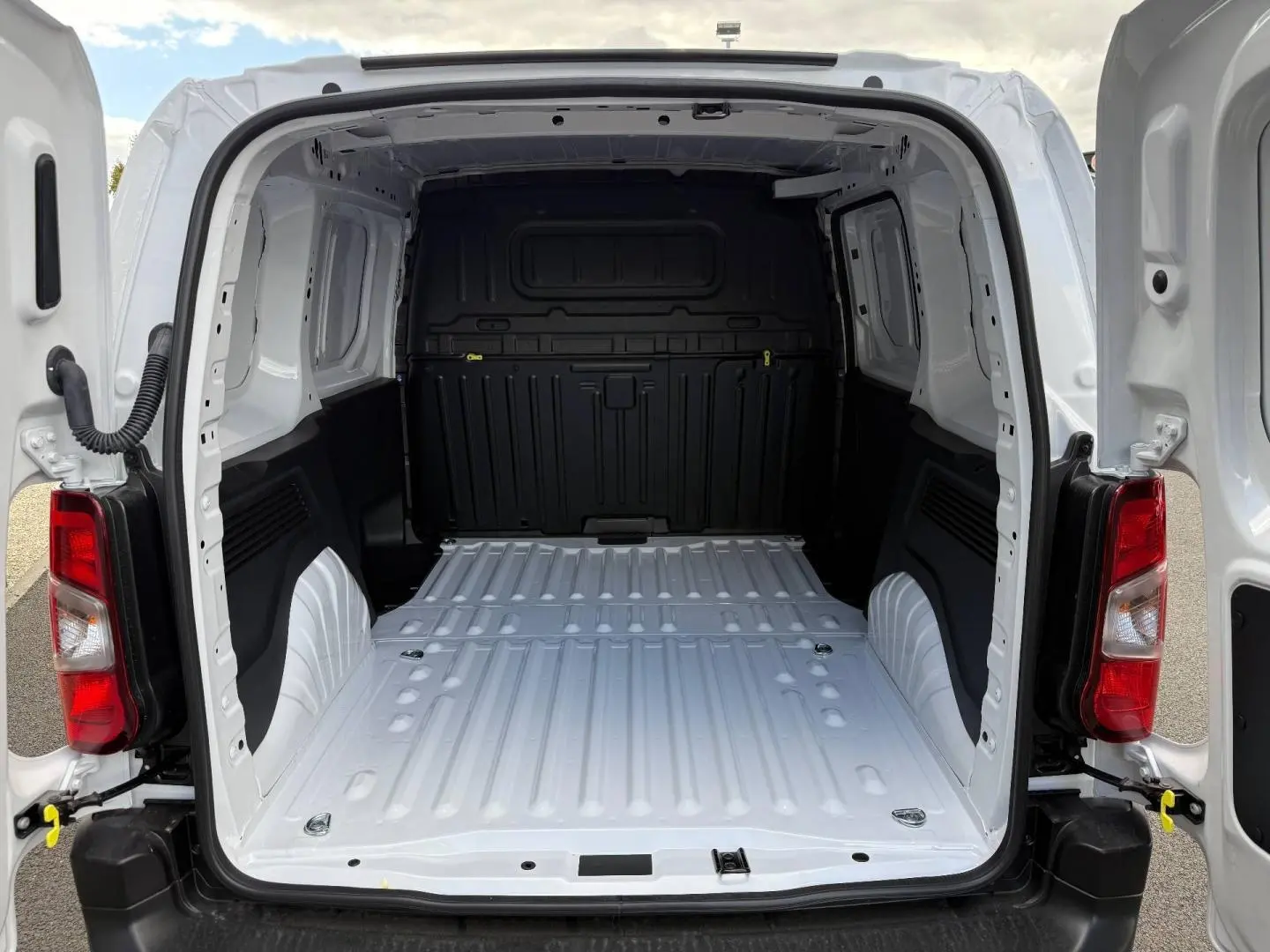 Vue arrière ouverte du Peugeot Partner blanc Icy 2026, montrant l'espace de chargement vide et la cloison noire intérieure.