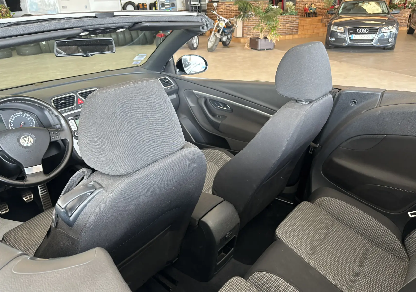 Intérieur du cabriolet Volkswagen EOS 2008, vue arrière montrant les sièges noirs et la planche de bord côté gauche.