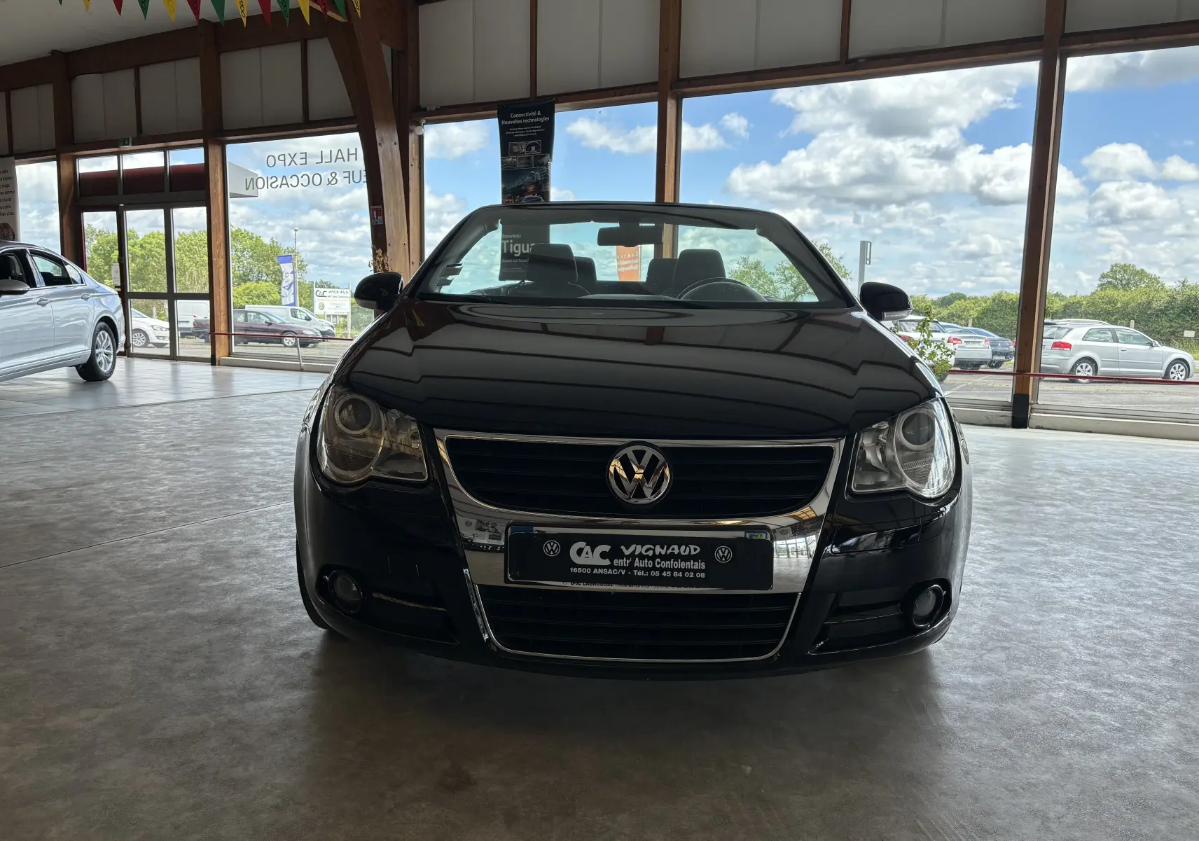 Vue de face d'une Volkswagen EOS noire en intérieur, soulignant sa calandre chromée et ses phares ronds.