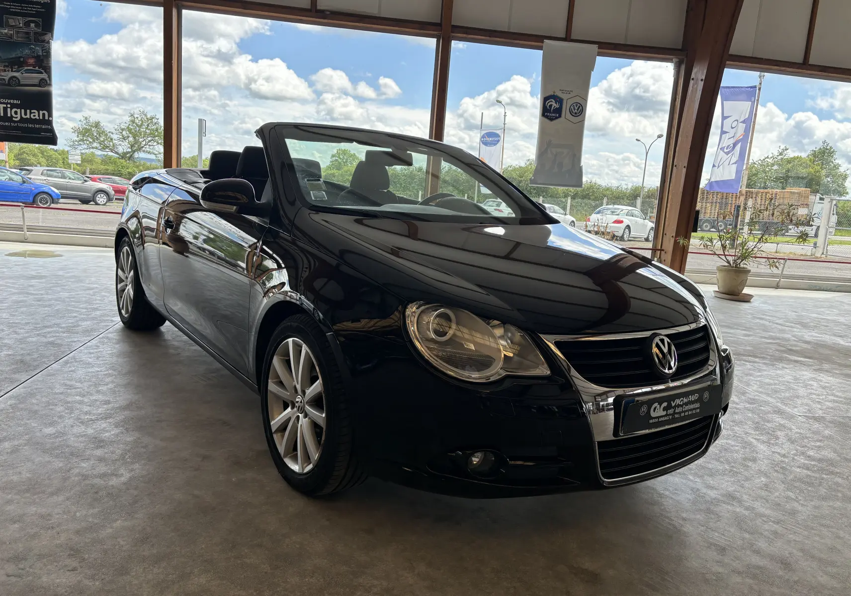 Volkswagen EOS cabriolet noir vu de 3/4 avant droit en intérieur, soulignant ses jantes alliage et phares ronds.