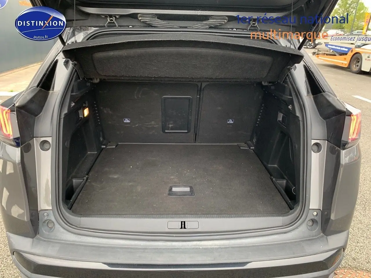 Coffre ouvert d'un Peugeot 3008 gris platinium metal vu de l'arrière, montrant un espace de chargement spacieux et propre.