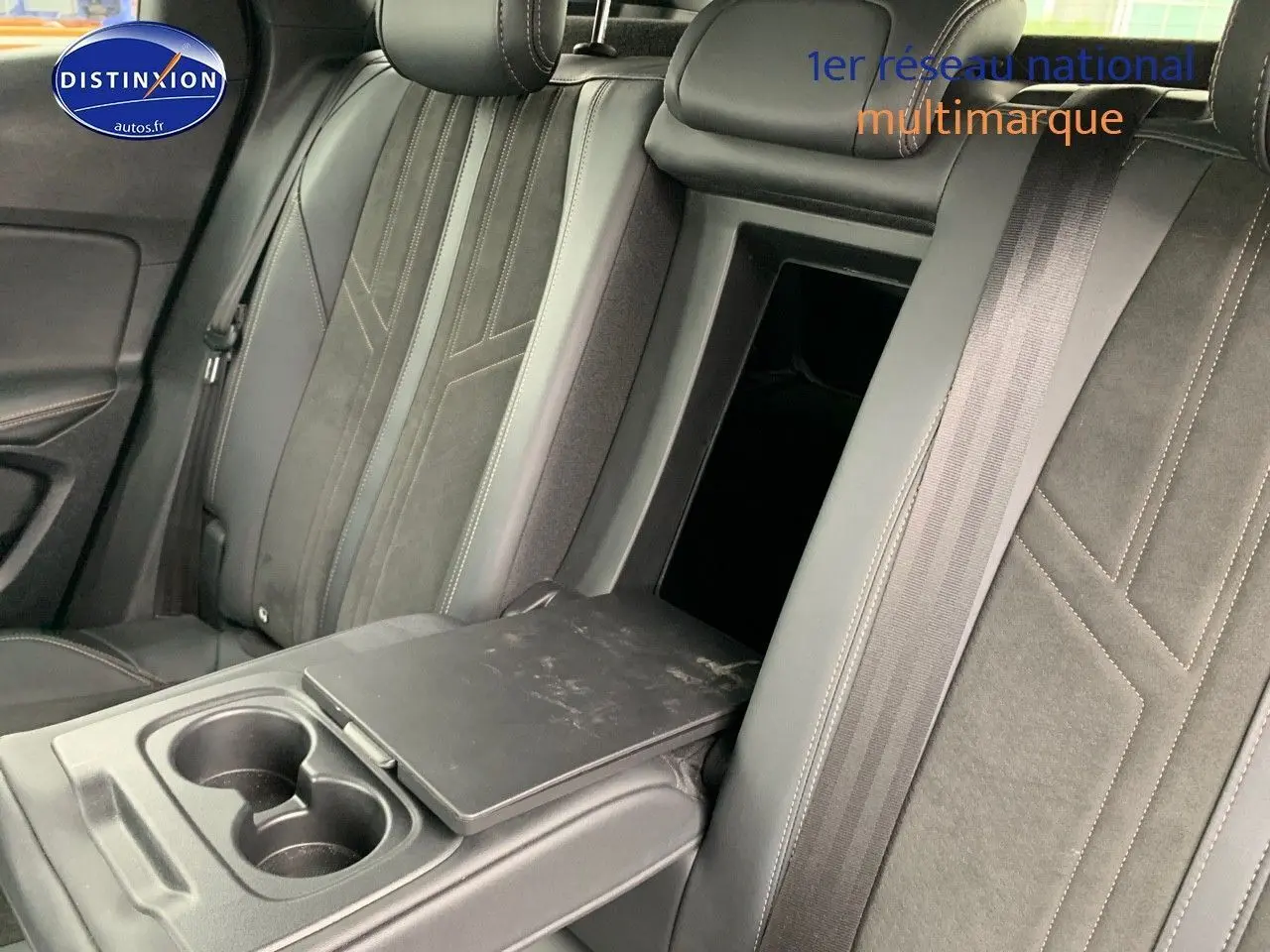Vue rapprochée de la banquette arrière en cuir noir du Peugeot 3008 gris platinium, avec accoudoir central et porte-gobelets ouverts.