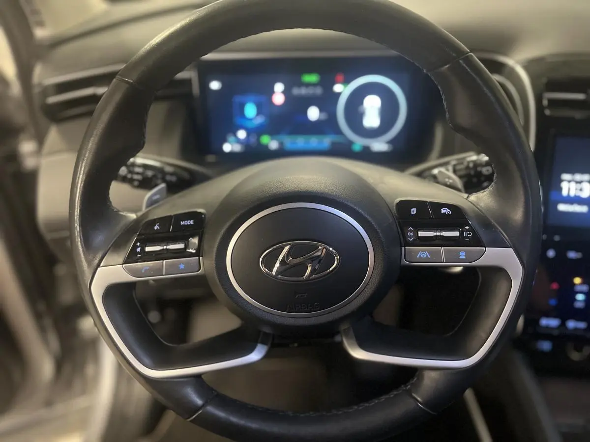 Volant cuir noir avec commandes intégrées du Hyundai Tucson 2023, affichage numérique flou en arrière-plan