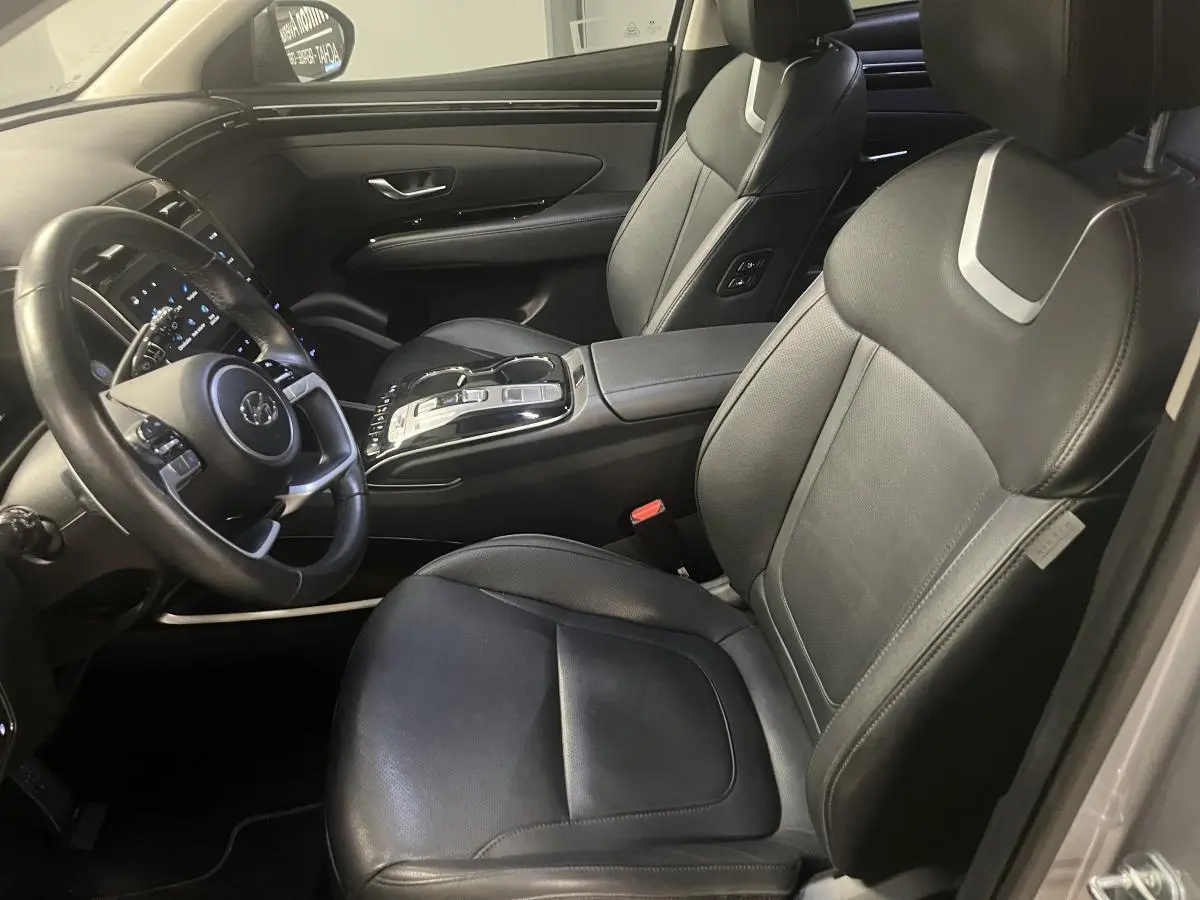 Vue intérieure côté conducteur du Hyundai Tucson 2023 avec sièges cuir noirs et console centrale moderne.