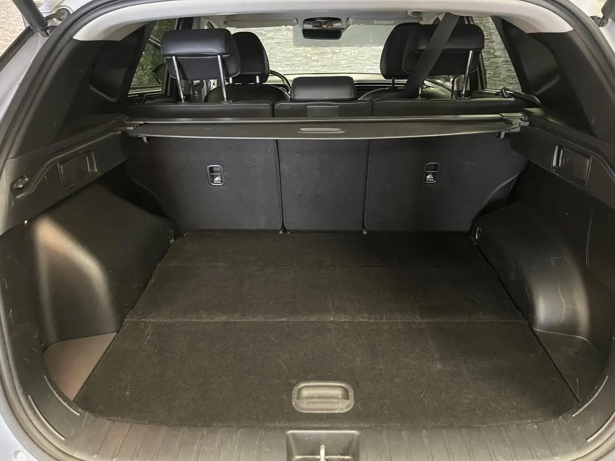 Coffre spacieux du Hyundai Tucson gris 2023 vu de l'arrière avec cache-bagages et sièges arrière rabattus.