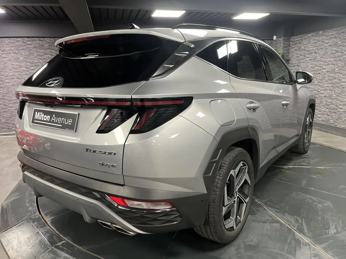 Vue 3/4 arrière droite du Hyundai Tucson gris métallisé 2023 avec feux arrière LED et double sortie d'échappement chrome.