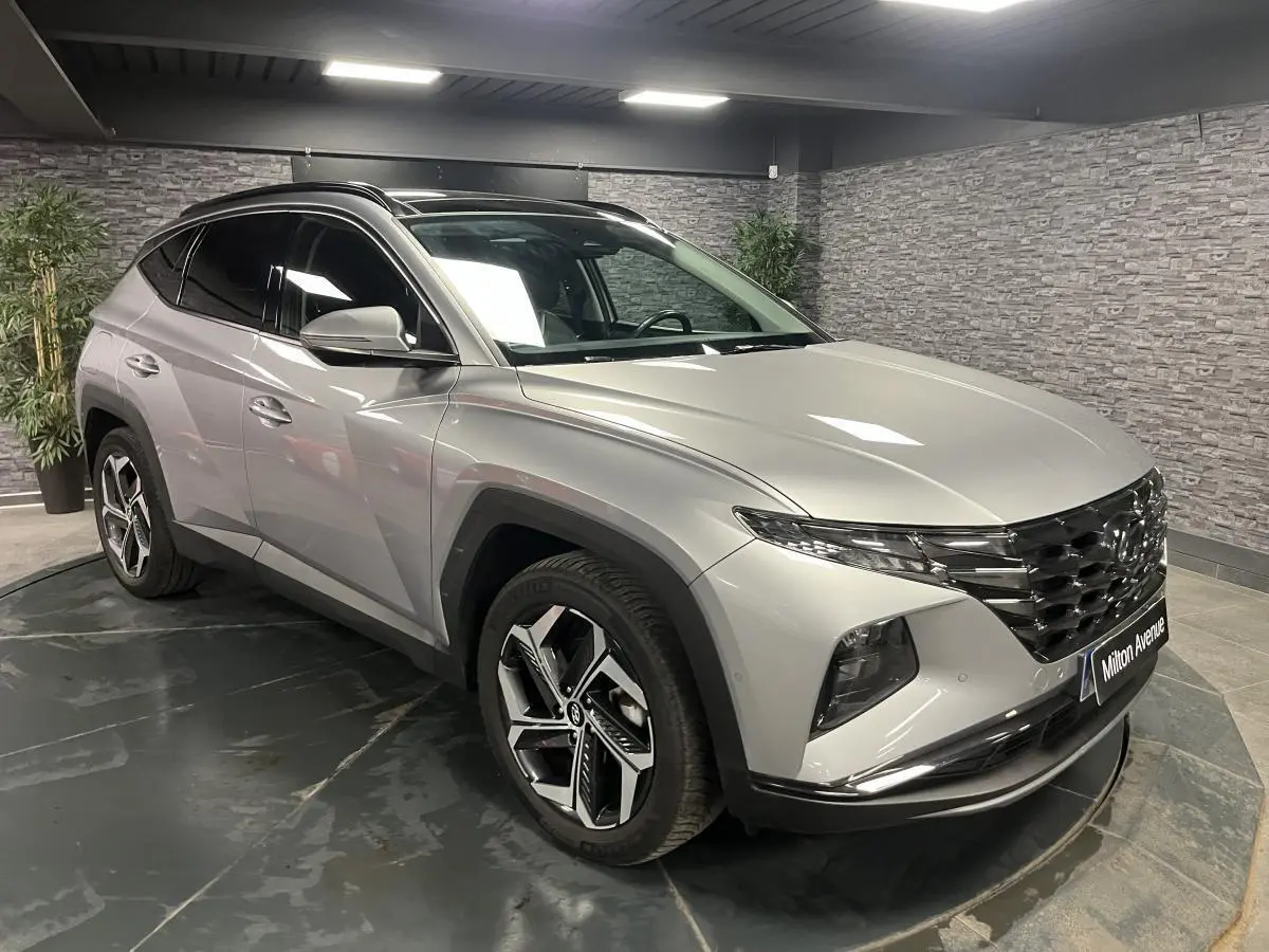 Vue 3/4 avant droite du Hyundai Tucson gris métallisé 2023 avec calandre noire et jantes alliage distinctives.