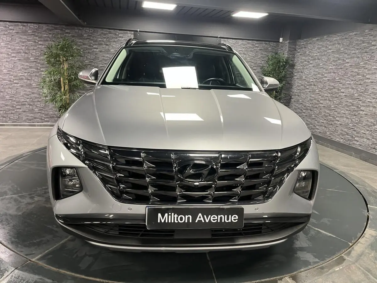 Vue frontale d'un Hyundai Tucson gris métallisé avec calandre noire brillante et phares intégrés.