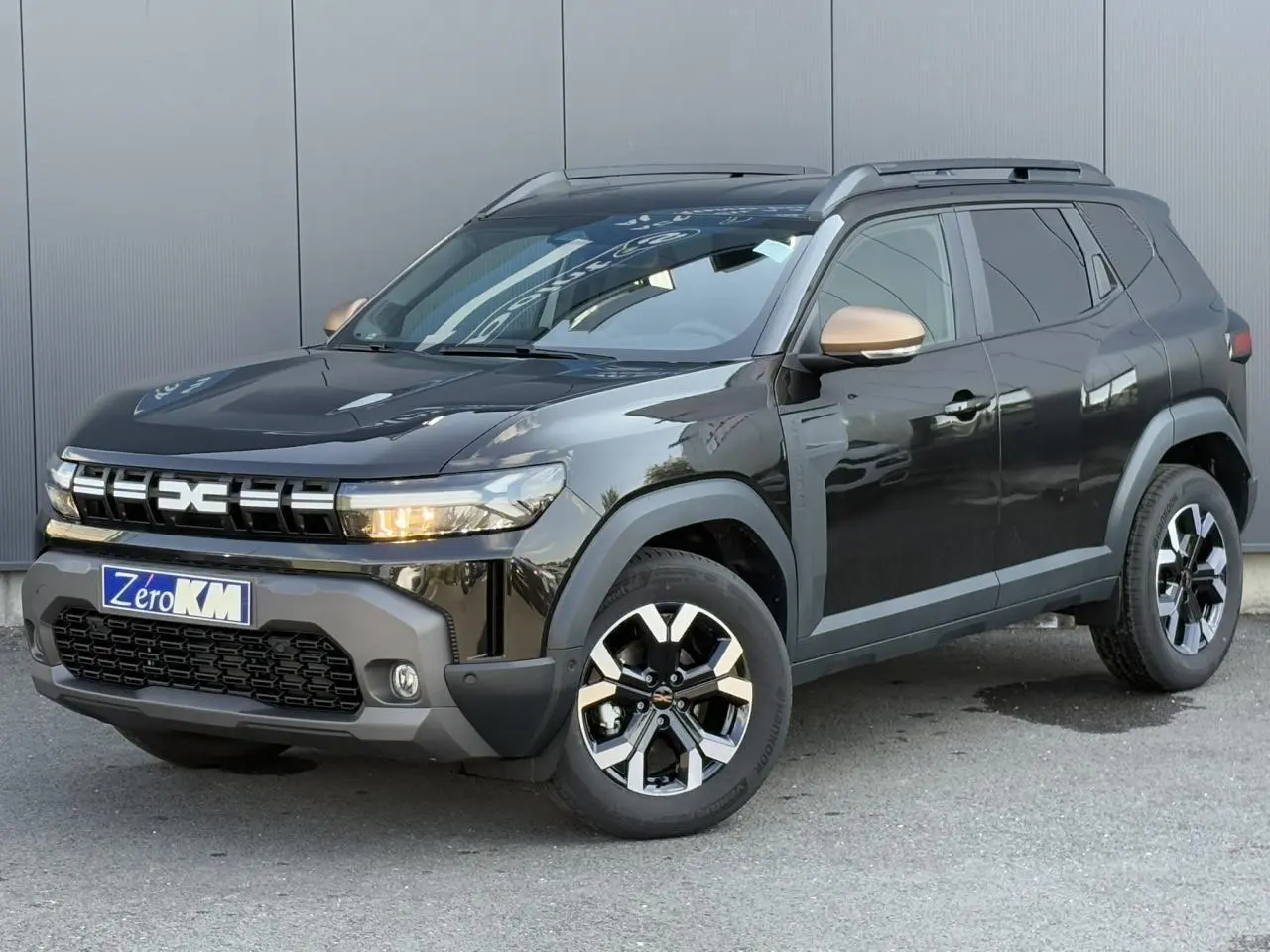 Dacia Duster noir nacré vu 3/4 avant droit avec coques de rétroviseur brun cuivré et jantes alliage 17 pouces.