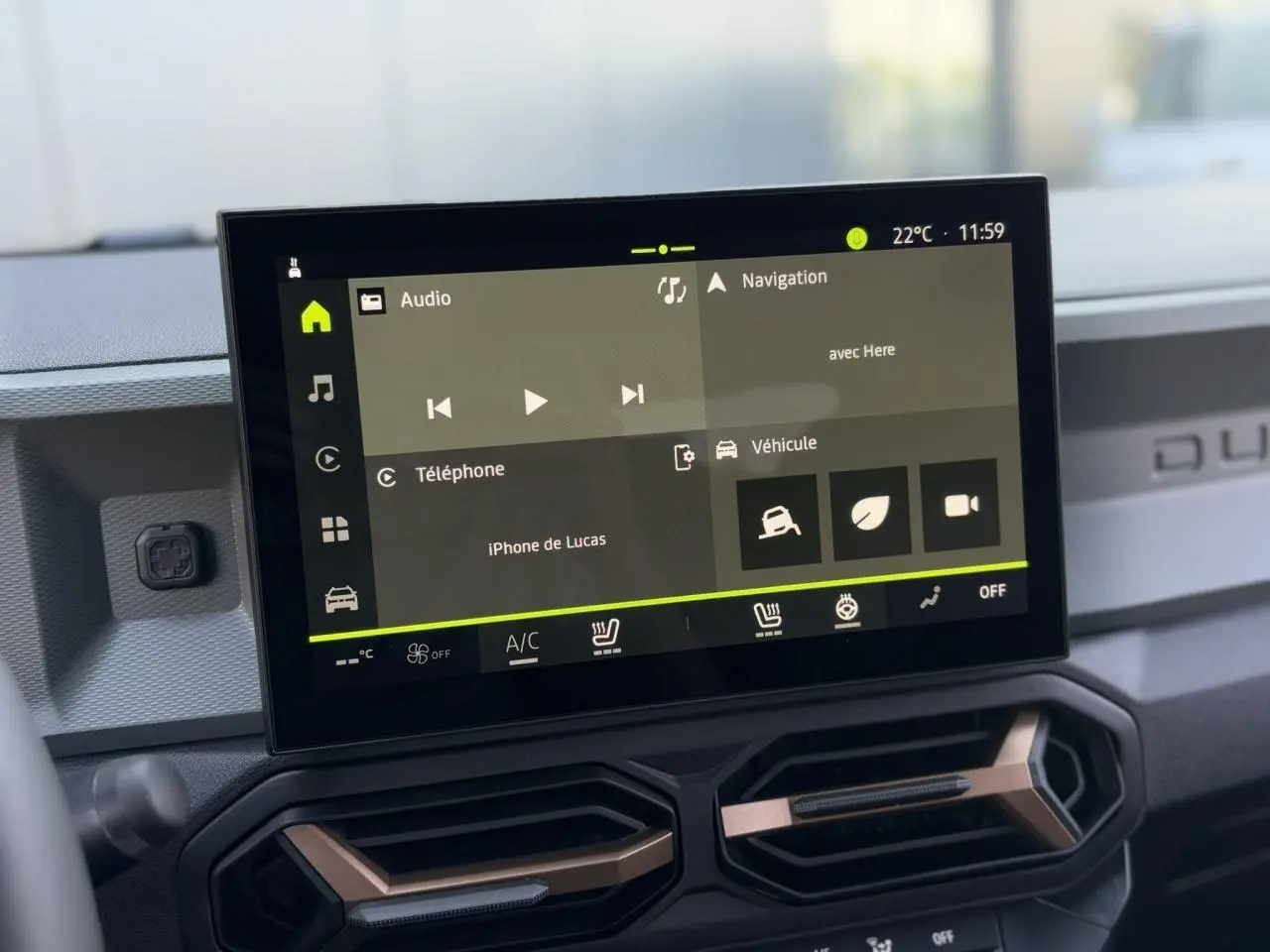 Écran tactile 10 pouces du tableau de bord du Dacia Duster 2025 avec commandes climatisation et finition brun cuivré.