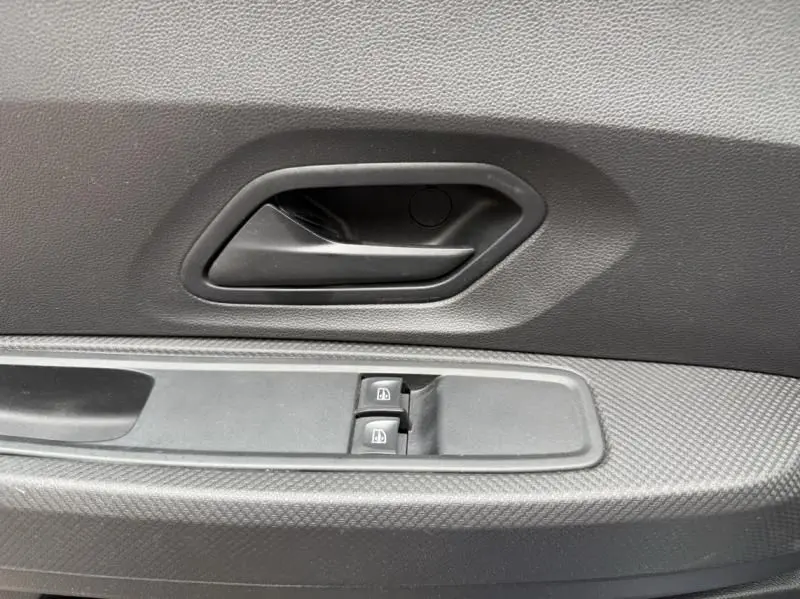 Poignée intérieure de porte côté gauche avec commandes de lève-vitres sur DACIA SANDERO STEPWAY bleu métal 2022.