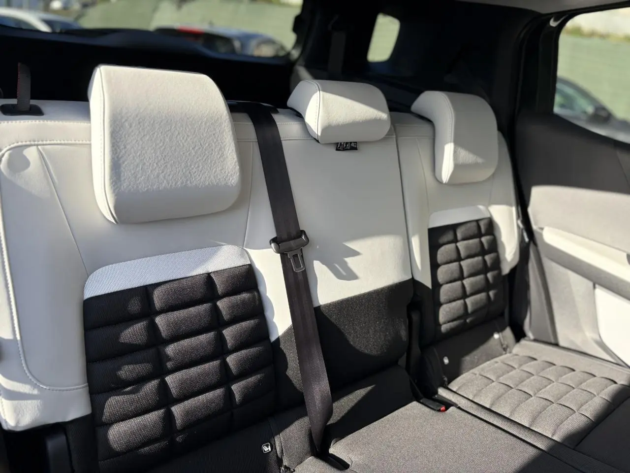 Vue rapprochée de la banquette arrière 3 places bicolore noire et blanche du Citroën C3 Aircross Hybrid 2025.