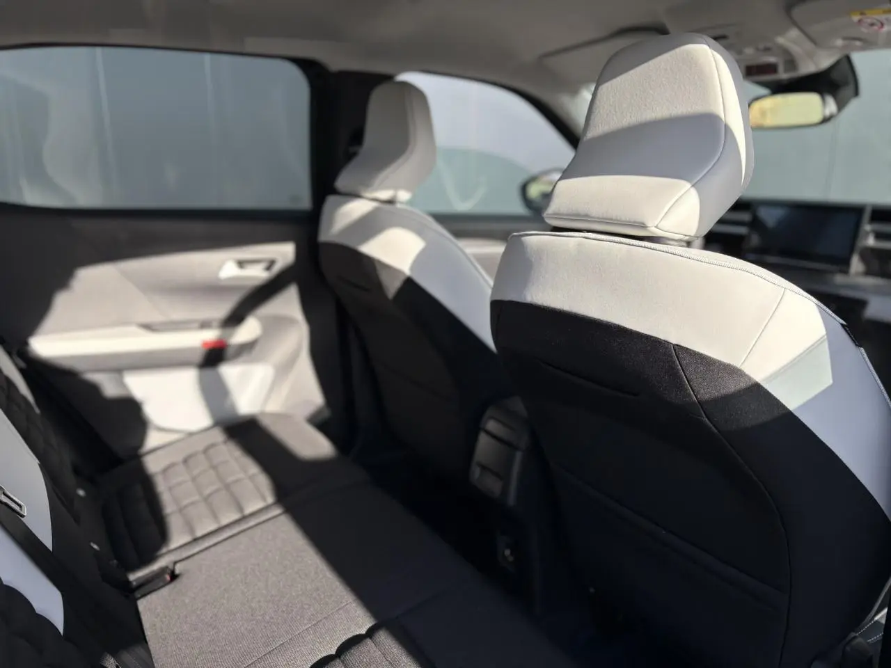 Vue intérieure côté gauche montrant les sièges arrière et avant en tissu gris clair et noir du Citroën C3 Aircross Hybrid 2025.