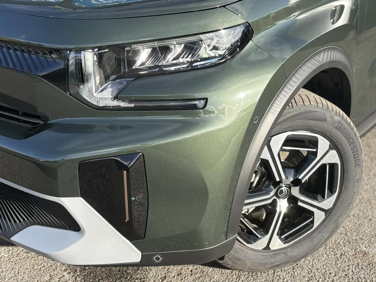 Gros plan sur l'avant droit du Citroën C3 Aircross 2025 en Vert Montana avec jante alliage et phares LED distinctifs.