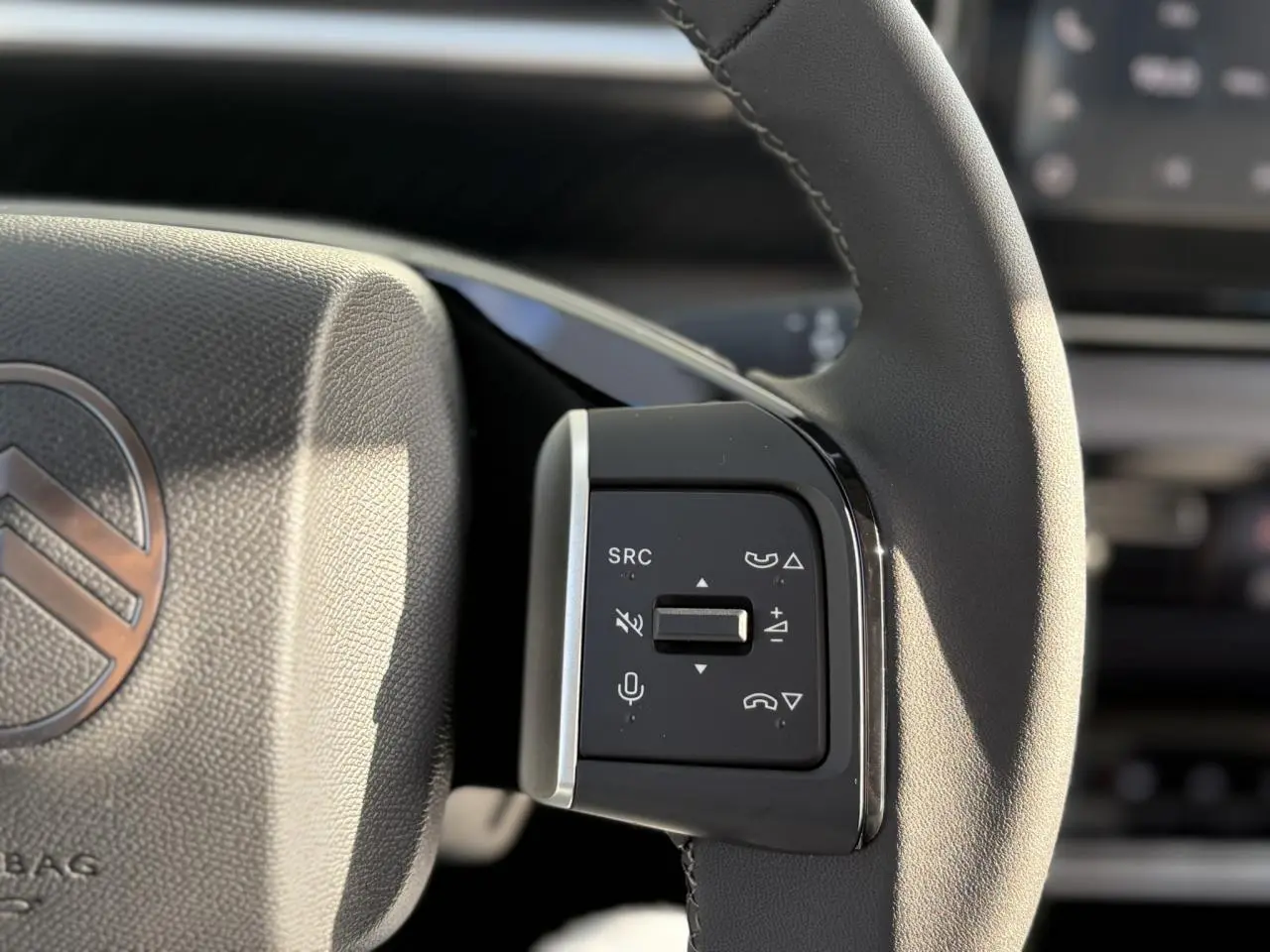 Gros plan sur les commandes multifonctions à droite du volant du Citroën C3 Aircross Hybrid 145, cuir noir.