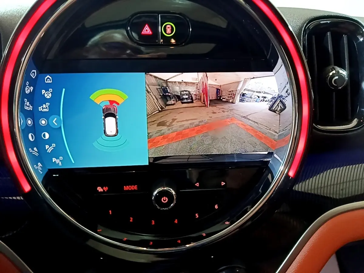 Affichage tactile circulaire du tableau de bord MINI Countryman bleu, montrant caméra de recul et capteurs de stationnement.