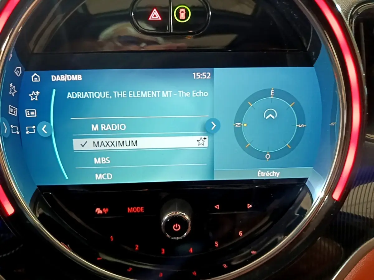 Écran tactile central du tableau de bord bleu de la MINI Countryman Cooper SE avec commandes circulaires et affichage radio.