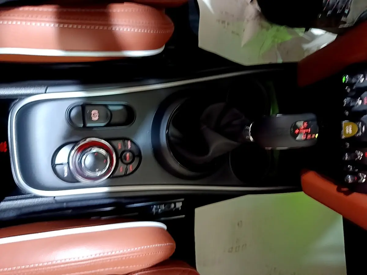 Vue plongeante sur la console centrale noire et les sièges en cuir marron du MINI Countryman Cooper SE 2021.