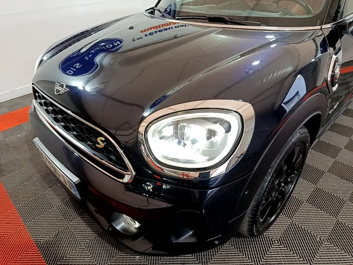 Vue 3/4 avant droit d'une MINI Countryman Cooper SE bleu foncé avec phares LED allumés et jantes noires.