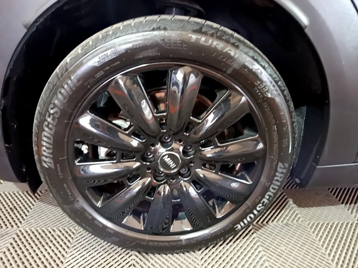 Gros plan sur la jante noire brillante et le pneu Bridgestone d'une MINI Countryman bleu 2021 côté avant droit.