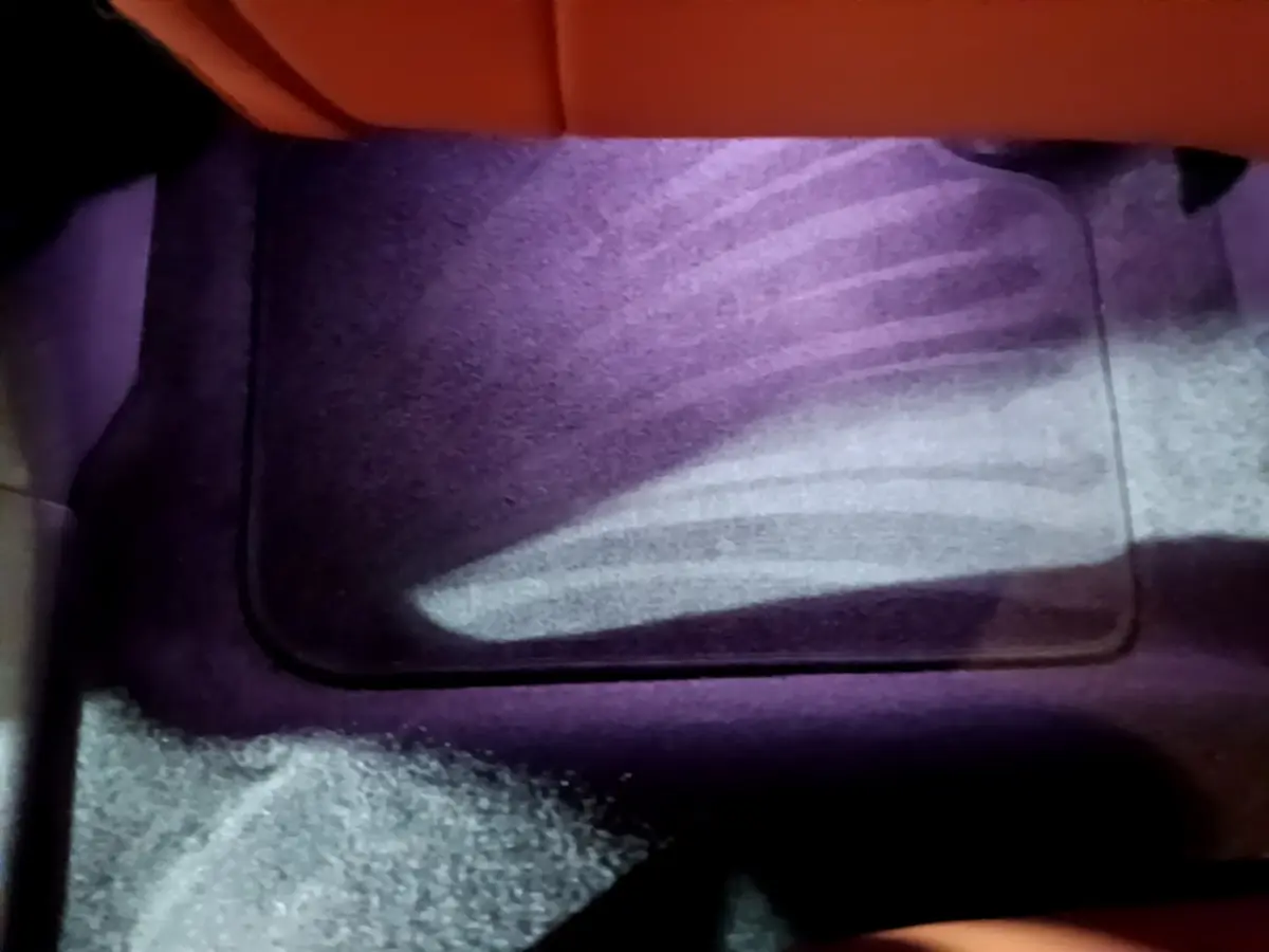 Plancher avant droit intérieur du MINI Countryman bleu 2021 avec tapis de sol et éclairage violet subtil.