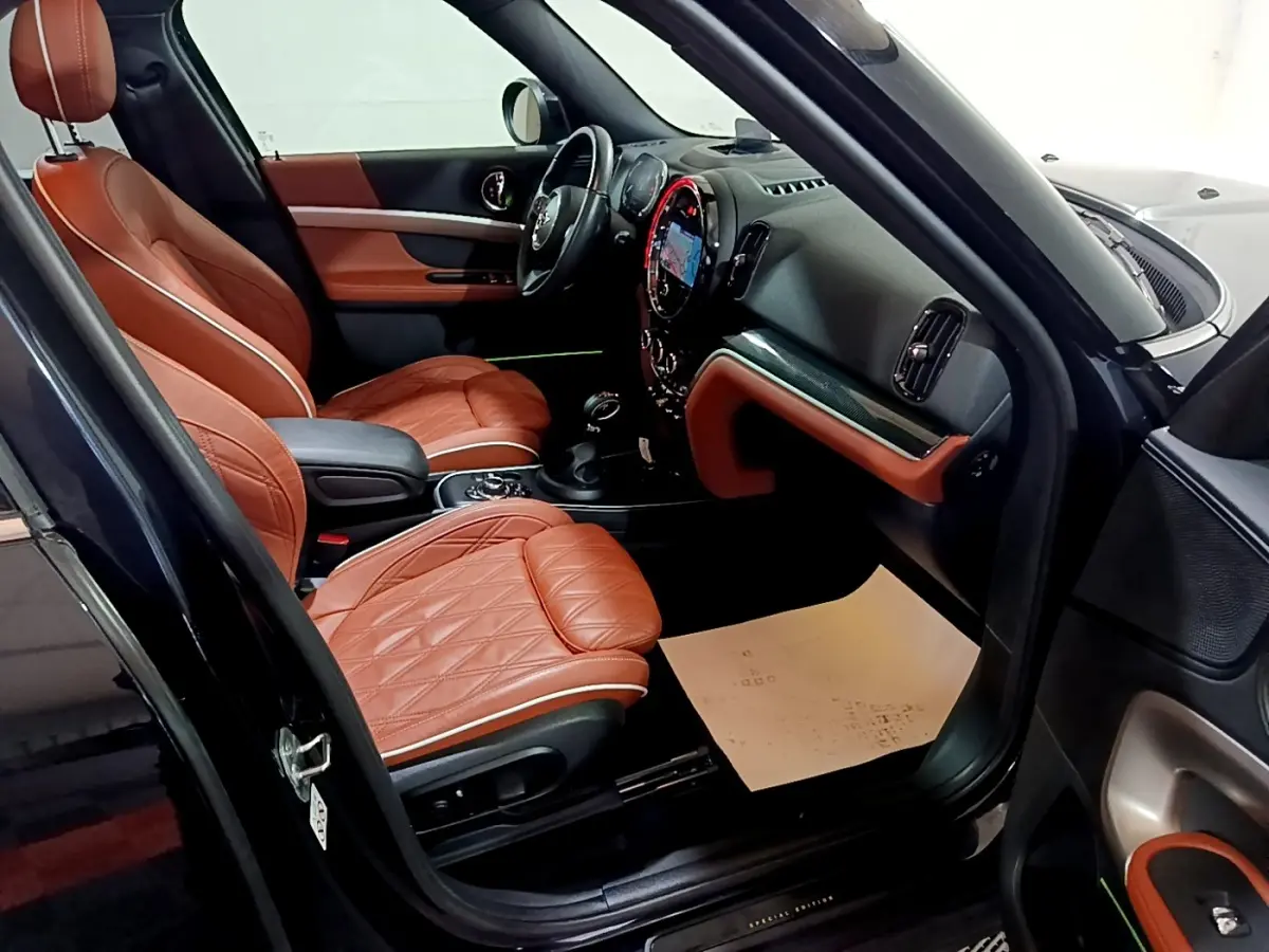 Intérieur avant droit d'une MINI Countryman bleu, sièges cuir marron matelassé et tableau de bord moderne.