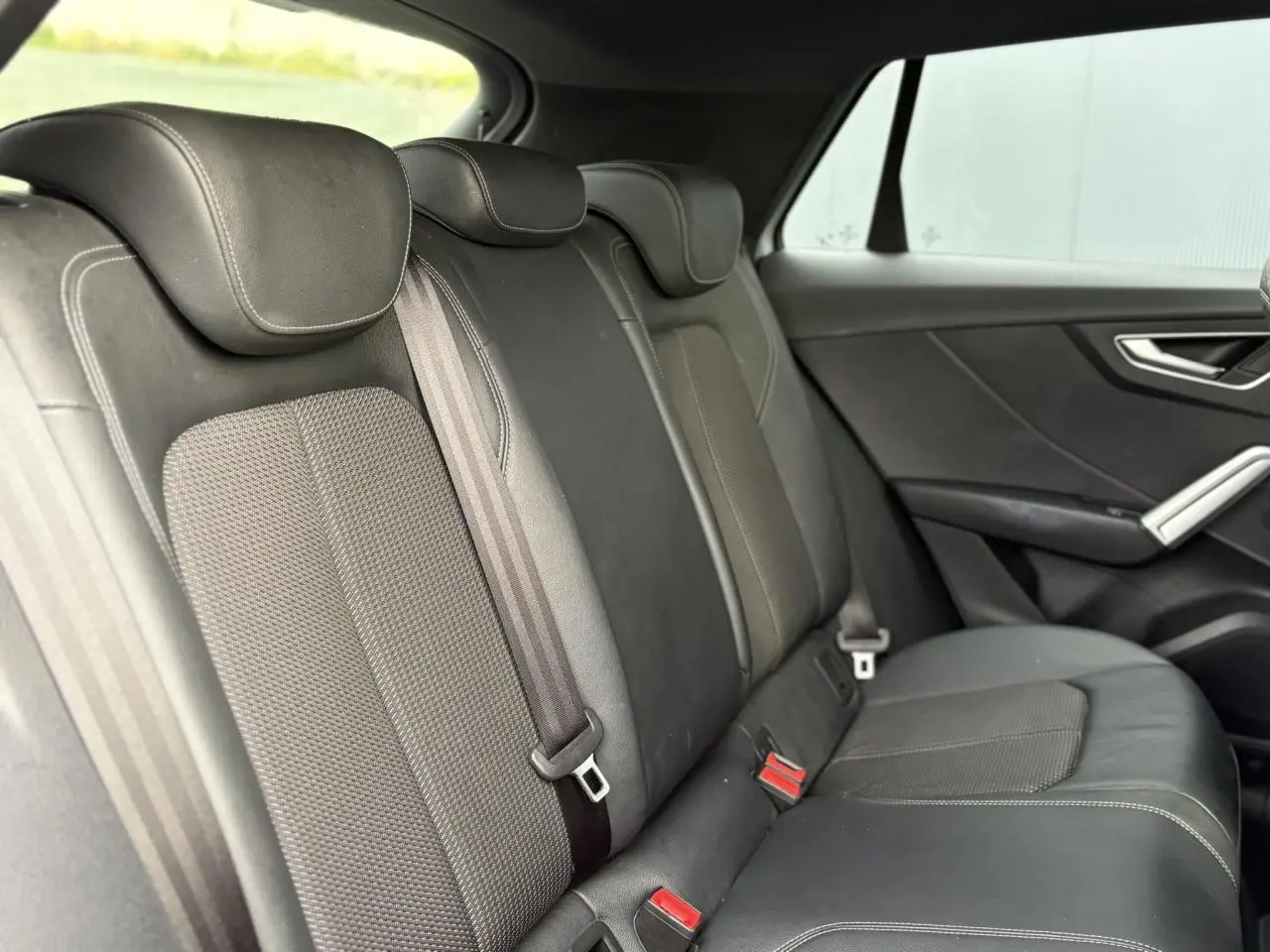 Vue latérale droite des sièges arrière en cuir et tissu gris foncé de l'Audi Q2 35 TDI S-Line 2025.
