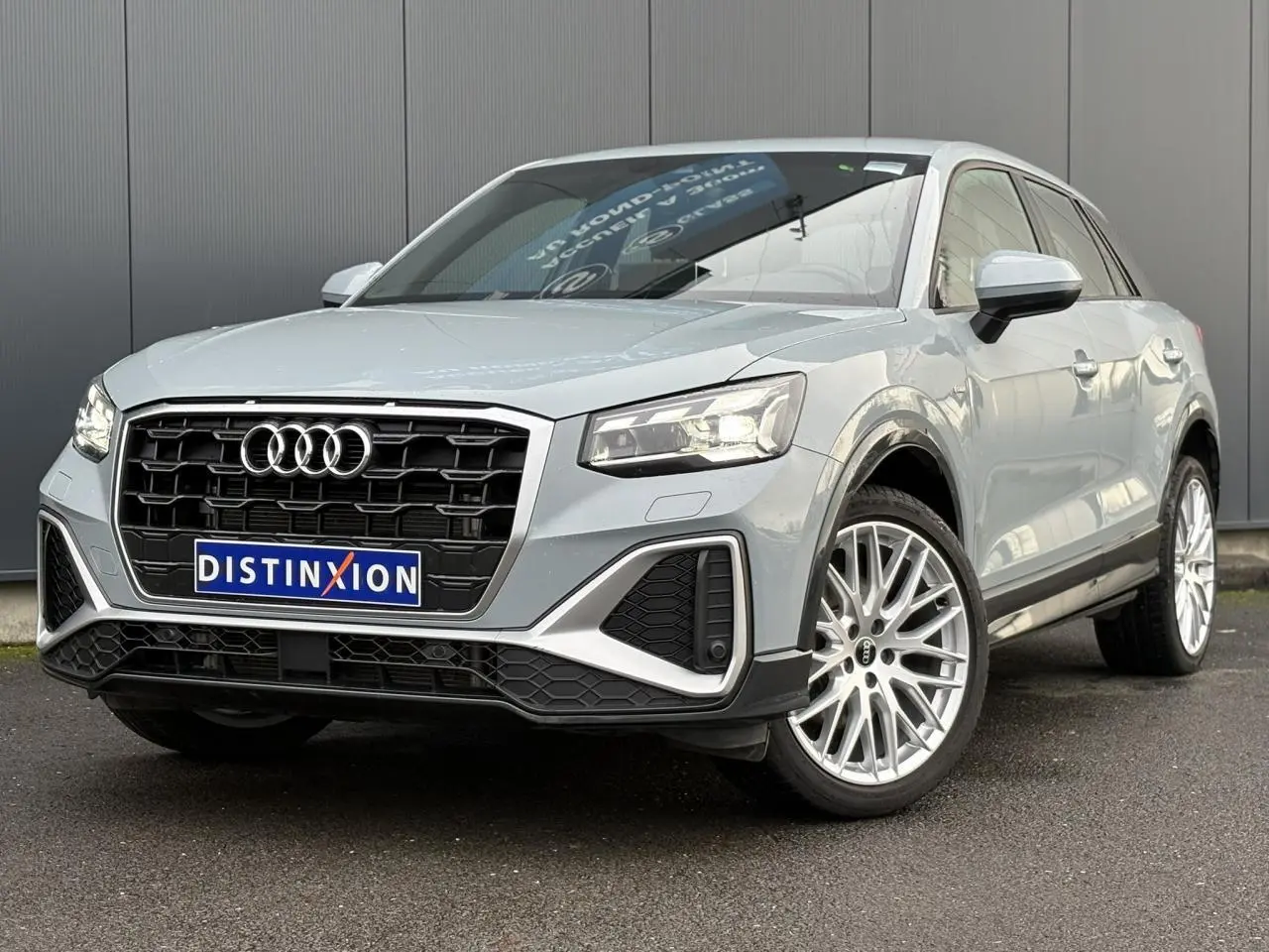 Audi Q2 35 TDI S-Line gris Flèche vue 3/4 avant droit, avec calandre noire et jantes alliage multibranches.