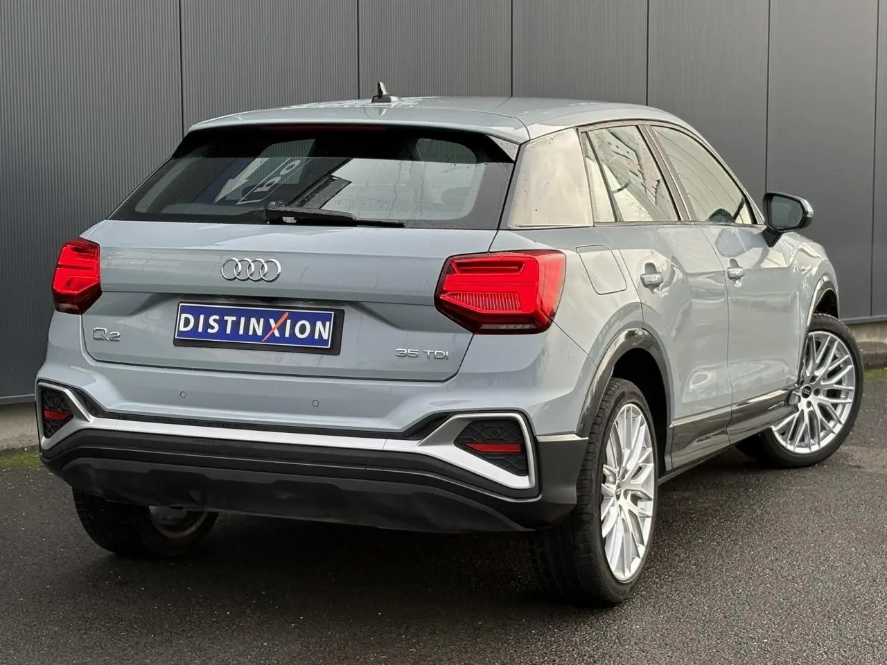 Audi Q2 35 TDI S-Line gris Flèche vue 3/4 arrière droit, avec feux LED et jantes alliage distinctives.