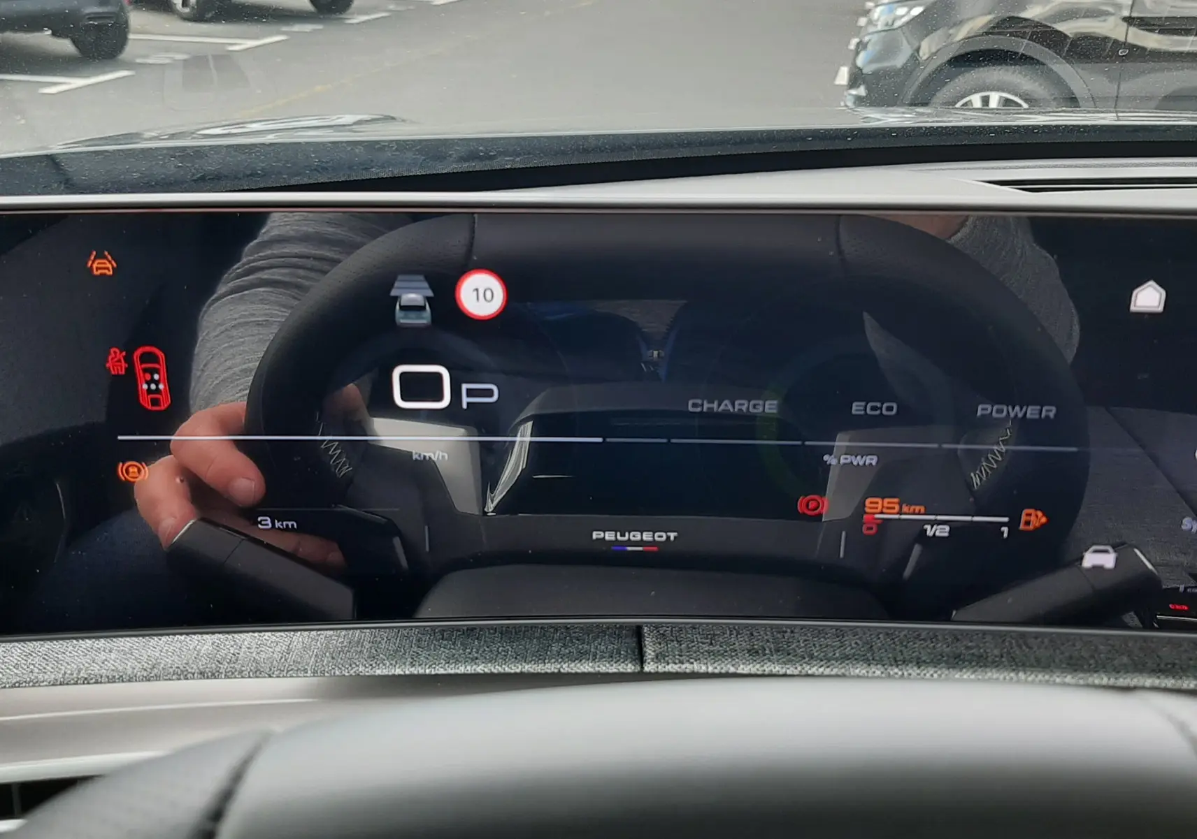 Vue intérieure du tableau de bord numérique du Peugeot 3008 gris titane, affichant les indicateurs de charge et vitesse.