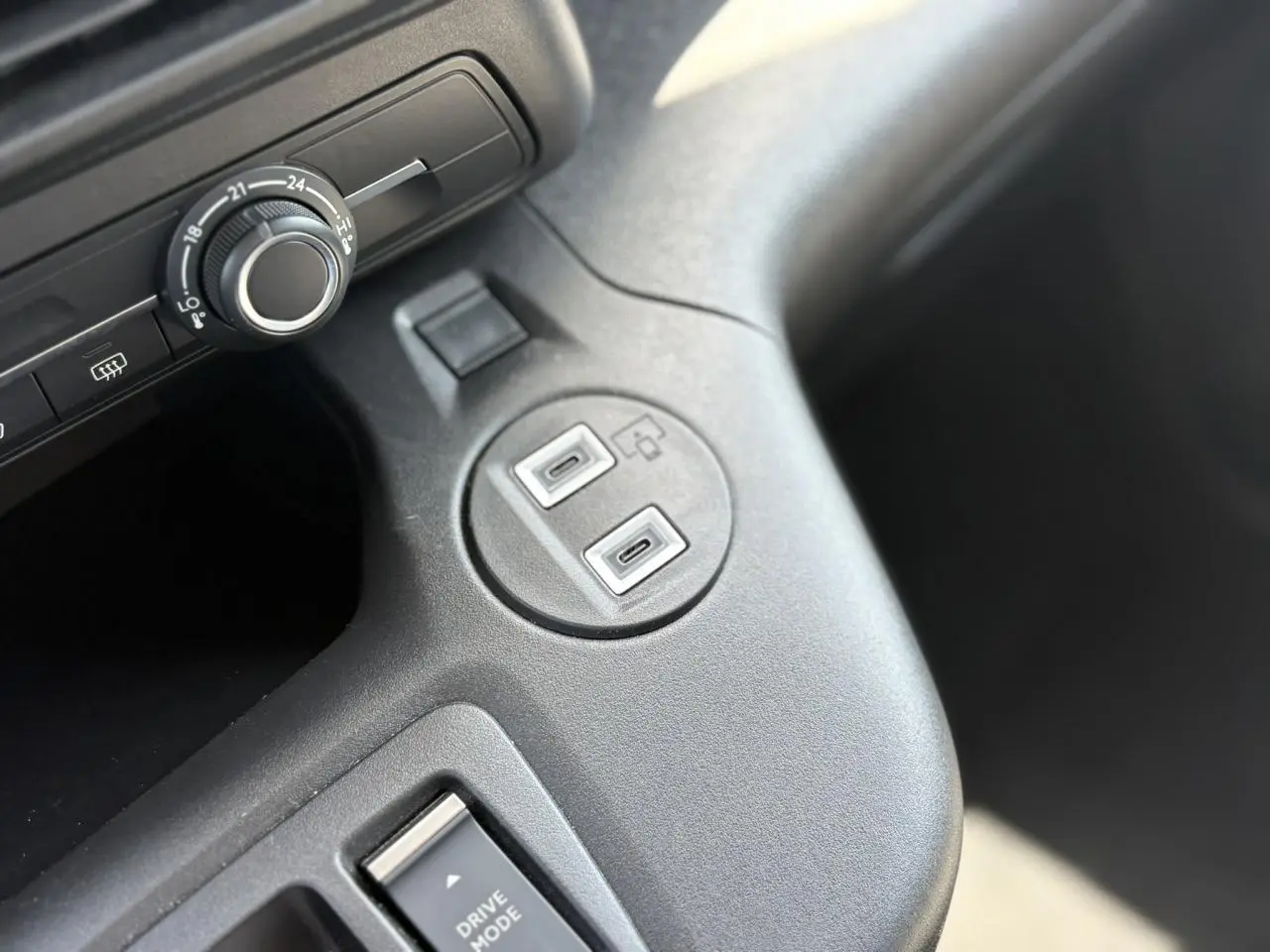 Gros plan sur la console centrale intérieure du Citroën Berlingo ë-136 bleu Kiama, montrant les ports USB et le bouton de réglage.