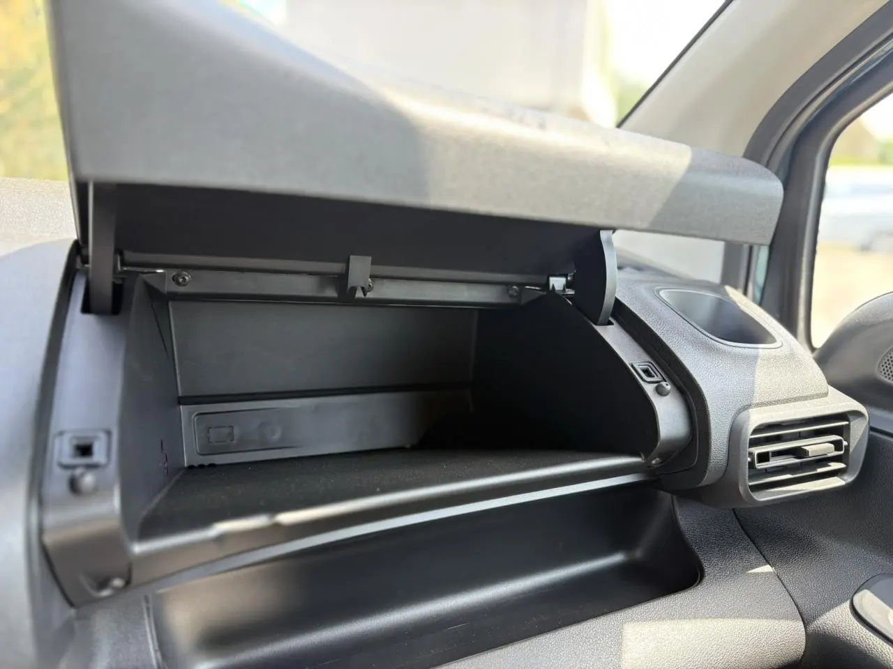 Vue rapprochée de la boîte à gants ouverte côté passager dans l’habitacle du Citroën Berlingo ë-136 bleu Kiama.