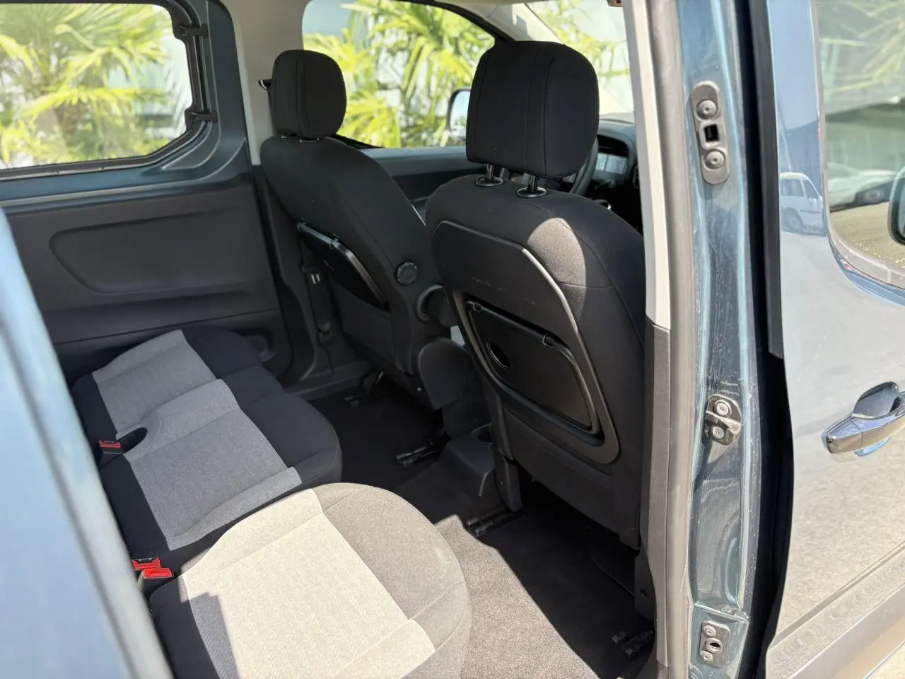 Vue intérieure côté droit du Citroën Berlingo ë-136 54kWh bleu Kiama, montrant les sièges arrière et banquette rabattable.